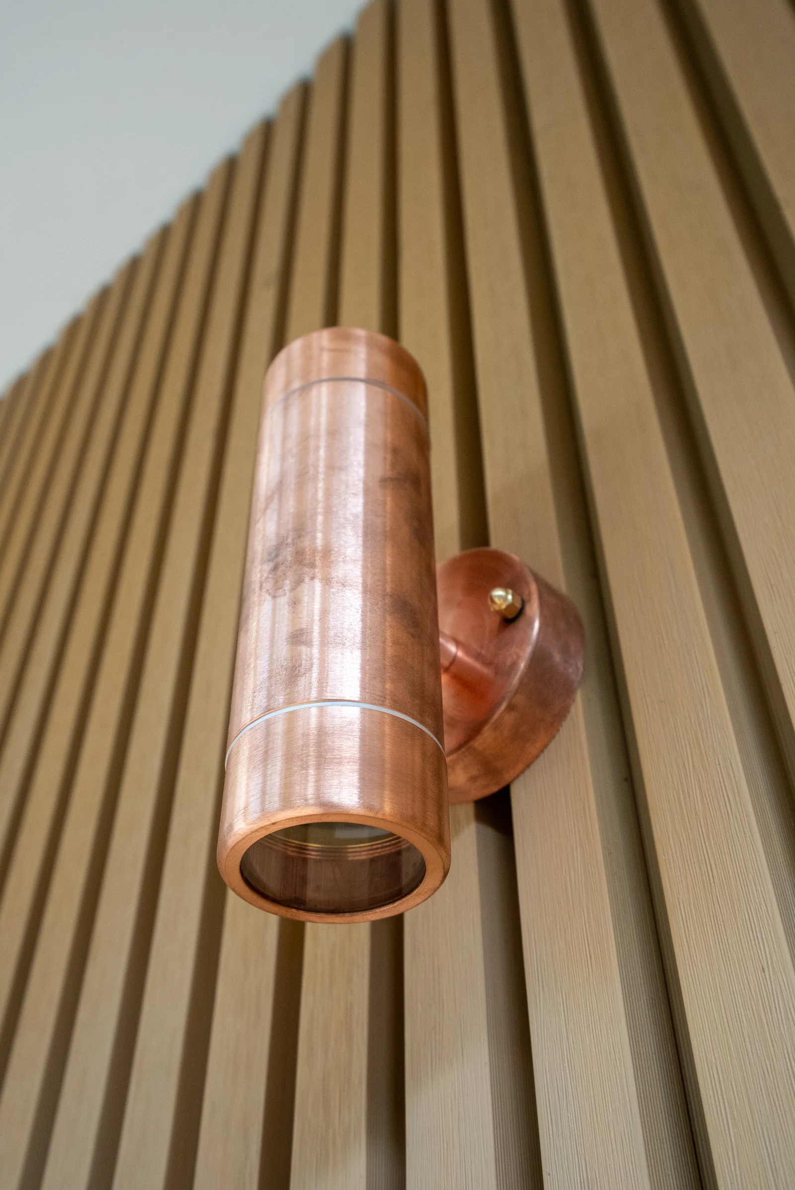 Copper wall light mounted on the vertical batten wall